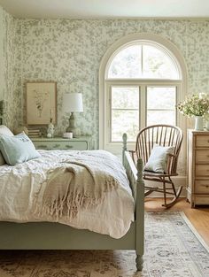 a bed sitting in a bedroom next to a window with a chair and lamp on top of it