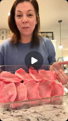 a woman standing in front of a glass bowl filled with raw meat