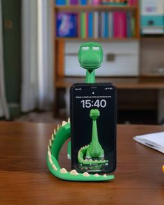 a green phone holder sitting on top of a wooden table next to a book shelf