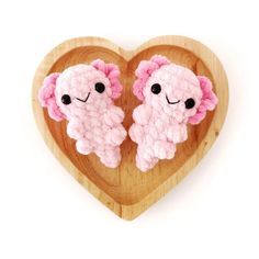 two stuffed animals sitting on top of a wooden heart