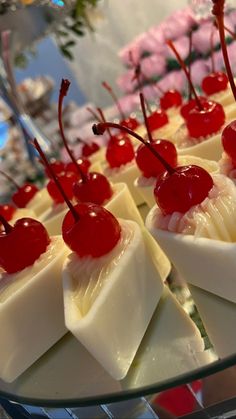 desserts with cherries and cheese are arranged on a glass platter for display