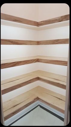 the corner of an empty room with wood slats on the walls and flooring