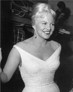 an old black and white photo of a woman in a dress smiling at the camera