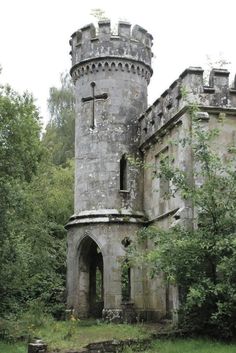 an old stone castle with a cross on the front and side entrance, surrounded by trees