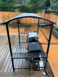 an outdoor grill on a wooden deck in the rain