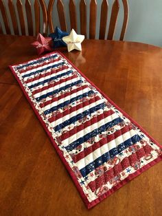 an american flag table runner sitting on top of a wooden table next to two stars