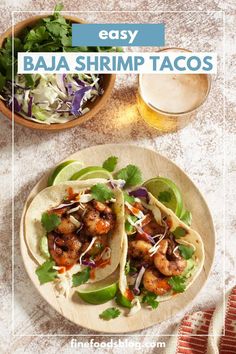 two tacos on a plate next to a glass of beer