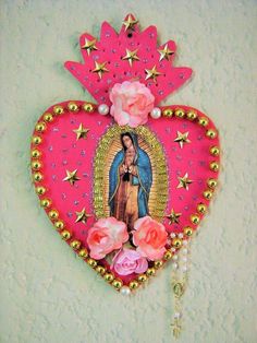 an image of the virgin mary on a pink heart with flowers hanging from it's side