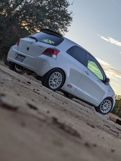 a small white car parked on top of a sandy beach