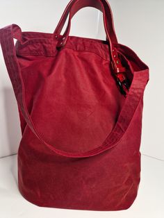 This red waxed canvas tote bag is a handmade and unique accessory that is perfect for everyday use, whether for shopping or running errands.  The bag is crafted from high-quality, sturdy waxed canvas fabric that is both durable and water-resistant. The bag's vibrant red colour is eye-catching and adds a pop of colour to any outfit. The tote features s shoulder strap that allows you to carry it comfortably and easily over your shoulder and handles which are made from upcycled leather belt.  The bag's spacious interior provides room for your essentials, including your wallet, phone, keys, and other items. The bag's open top design makes it easy to access your belongings and the bag's contents, while also adding a casual and relaxed feel. The red waxed canvas tote bag is well-made, with stron Waxed Canvas Tote Bag, Waxed Canvas Bag, Upcycled Leather, Red Canvas, Red Colour, Waxed Canvas, Leather Handles, Accessories Unique, Vibrant Red