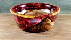 a red and yellow bowl sitting on top of a wooden table