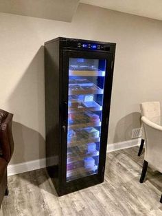 an empty wine cooler sitting in the corner of a room next to a leather chair