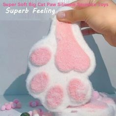 a person is holding a pink and white cat paw toy