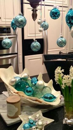 blue and white ornaments hang from the ceiling in a kitchen with marble countertops, stainless steel appliances, and glass vases