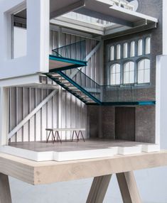 an architectural model of a building with stairs and tables in front of the entrance door