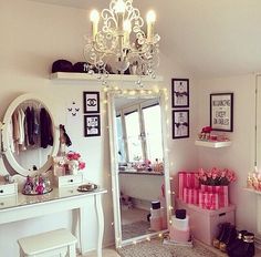 a room with a vanity, mirror and lights on the ceiling is decorated in pink and white