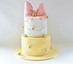 a three tiered cake decorated with honeycombs and a pink bow on top