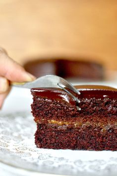 a piece of vegan chocolate cake on a white plate with a fork in it