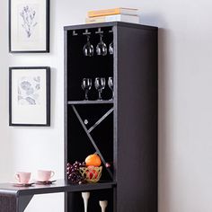 a black cabinet with wine glasses and fruit on it next to a table in a room