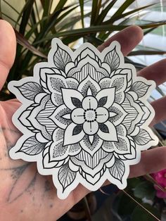 a hand holding a sticker with a flower design on it