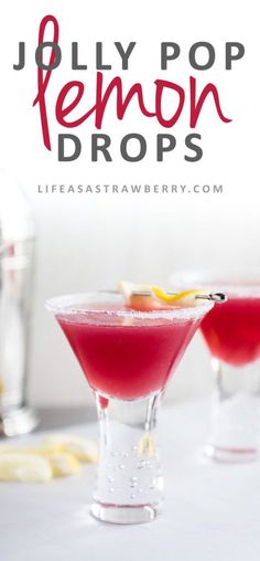 two glasses filled with red liquid sitting on top of a table next to lemon wedges