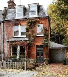 an old brick house with ivy growing on it's windows and door, surrounded by autumn foliage