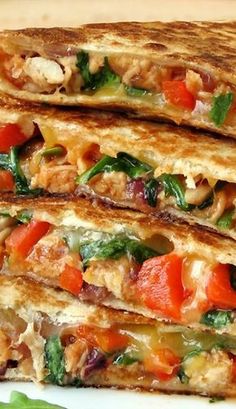 two quesadillas stacked on top of each other with vegetables and meats