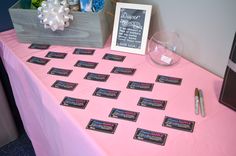 a pink table topped with lots of place cards and a chalkboard on top of it