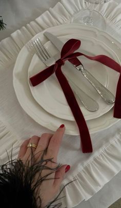 a table set with silverware and red ribbon