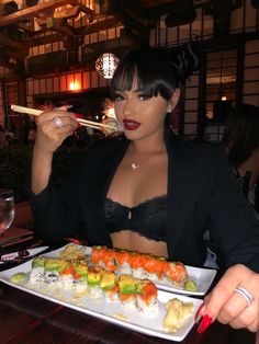 a woman eating sushi with chopsticks in her hand at a restaurant table