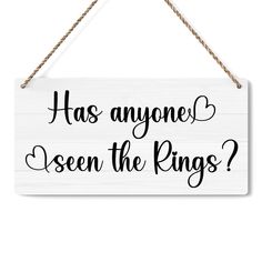 a white sign that says has anyone seen the rings? hanging from a rope on a wall