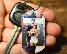 a person holding a keychain with a photo on it and a car key