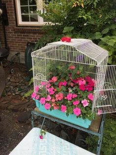 a white bird cage with pink flowers in it