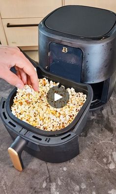 a person scooping popcorn into a black container