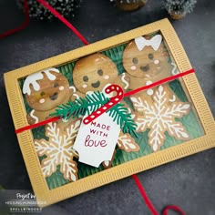 three decorated cookies in a box with a red ribbon tied around the edges and a sign that says made with love