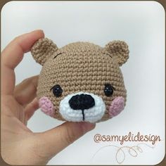 a small crocheted teddy bear is being held up by someone's hand