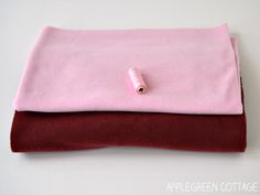 a pink and red blanket sitting on top of a white table next to a pair of scissors