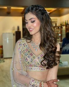 a woman with long hair wearing a bridal dress and jewelry on her hands, smiling at the camera