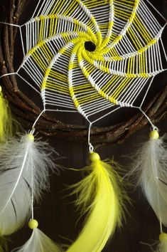 yellow and white feathers are hanging from a basket with some beads on it's side