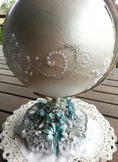 a silver ball sitting on top of a white doily covered table with beads around it