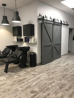 the inside of a hair salon with black chairs and wooden flooring, lights hanging from the ceiling