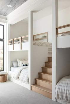 a bedroom with bunk beds and stairs leading up to the second floor, in front of a window