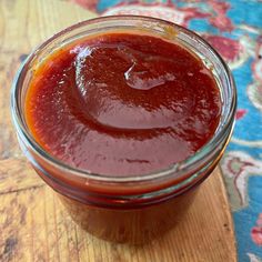 a glass jar filled with ketchup sitting on top of a wooden table