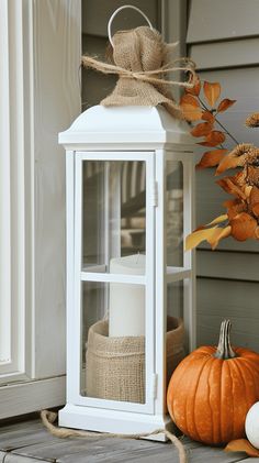 a white lantern sitting on top of a porch next to pumpkins and gourds