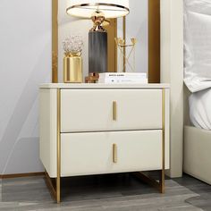 a white and gold nightstand with a lamp on top of it next to a bed