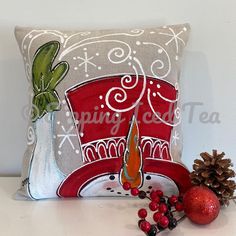 a decorative pillow with a red hat on it next to a christmas ornament