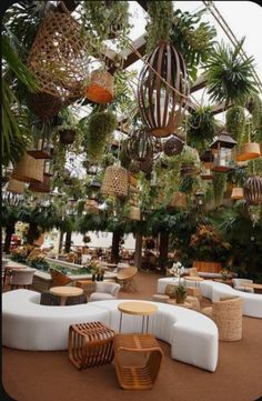 an outdoor seating area with lots of plants hanging from the ceiling and chairs around it