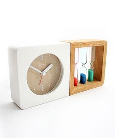 a white clock in a wooden box filled with colored candles and an hour on the side