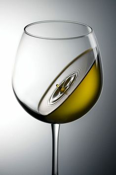 a close up of a wine glass with white wine in it's bottom half