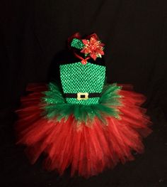 a red and green tutu skirt with a hat on top that is attached to a black background